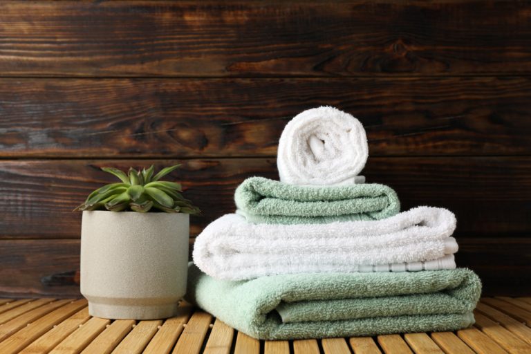 Towels and succulent plant on bamboo table against wood backgrou